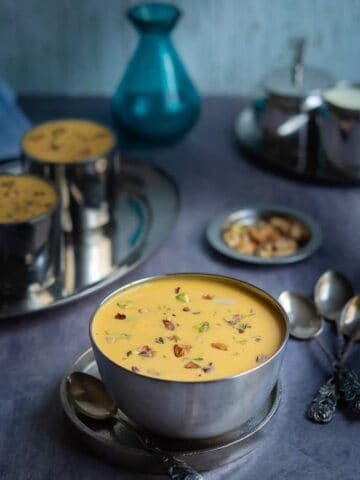 Carrot payasam displayed in stainless steel bowl with lots of nuts and raisins